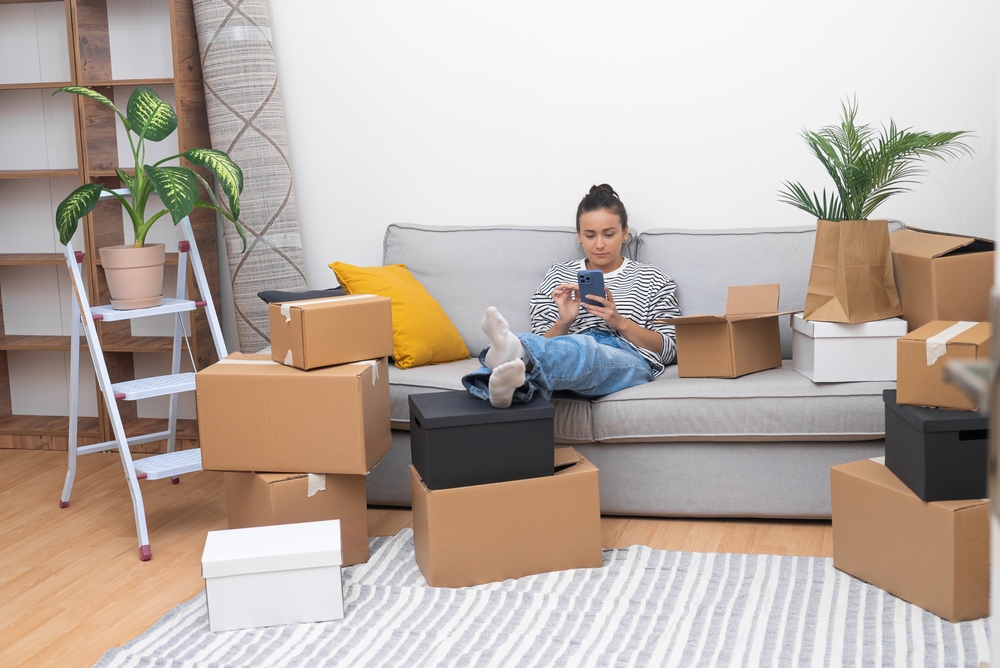 locataire consultant une offre d'assurance habitation sur son téléphone, assis dans son appartement