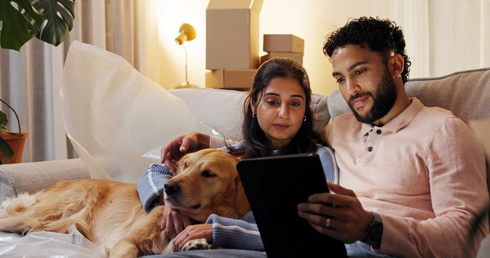 jeune locataire souriant regardant des annonces sur son ordinateur dans un café